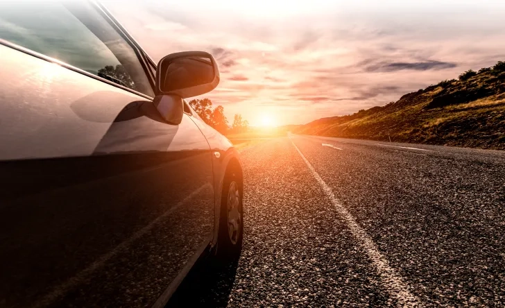 Voiture sur une route au coucher du soleil, illustration des trajets longue distance